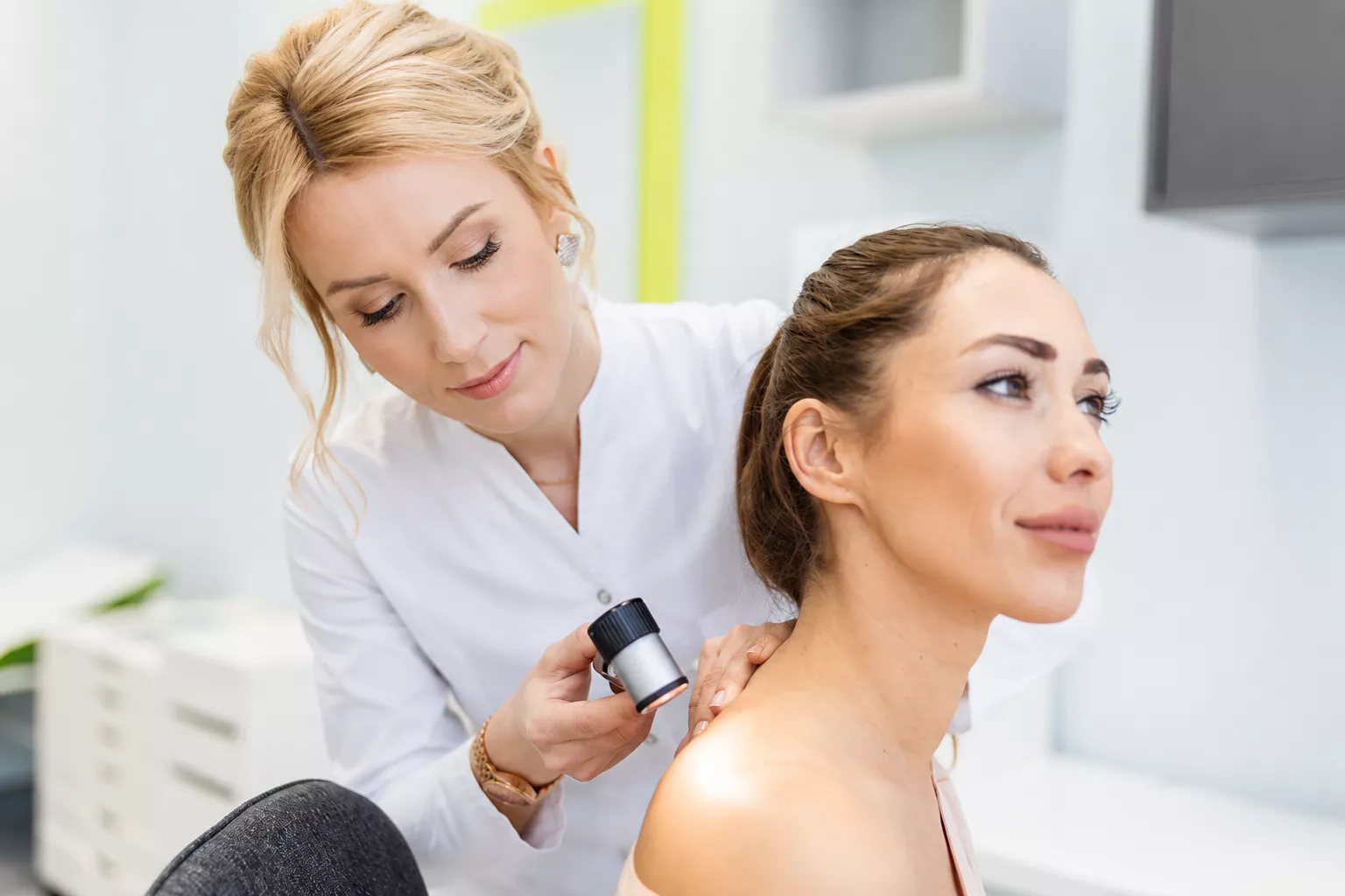 Врач-дерматолог осматривает кожу пациентки дерматоскопом в Profi Derm
